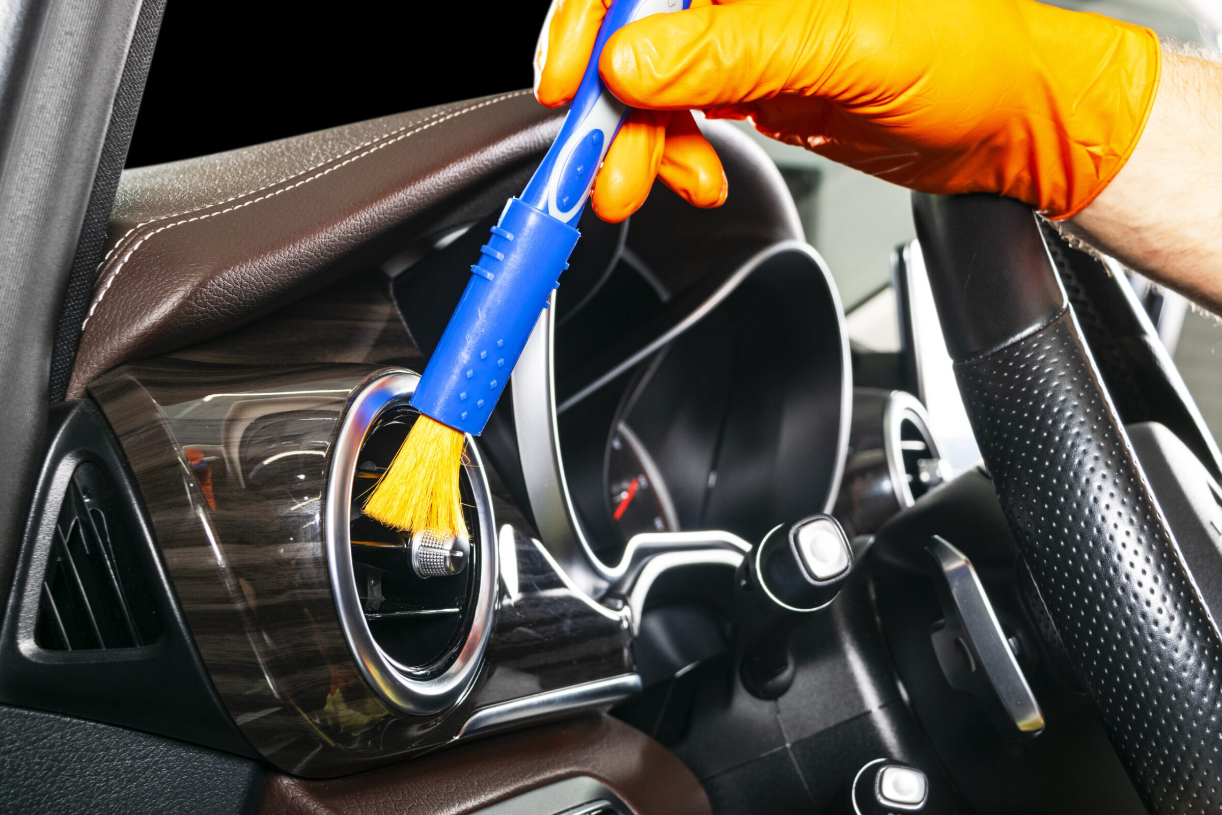 A man cleaning car with cloth and brush. Car detailing. Selective focus. Car detailing. Cleaning with brush. Worker cleaning. Brush and cleaning solution to clean.