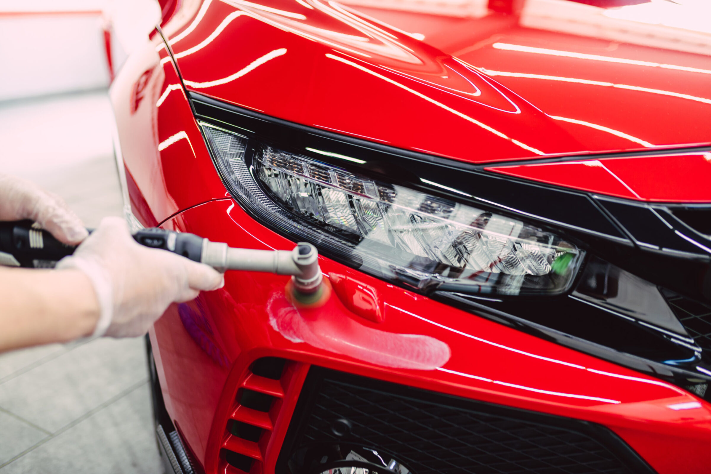 Car detailing - Worker with orbital polisher in auto repair shop.